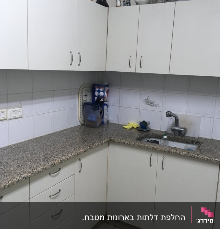 מטבח עם ארונות לבנים ומשטח עבודה גרניט